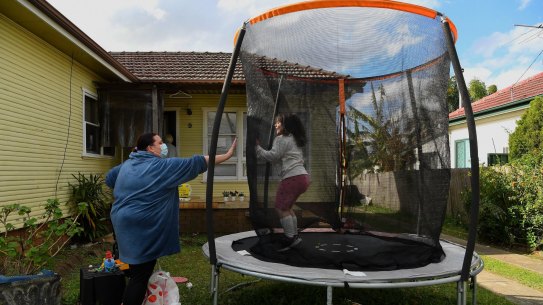 Maria Moschetti (left) plays with her 6 year old autistic daughter Lily Thomson (right) in the front yard of their home in Fairfield during the COVID-19 lockdown. Maria says that the community support has been one thing getting them through the lockdown. Fairfield, NSW. 16th September, 2021. Photo: Kate Geraghty 