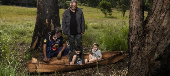 Uncle John Kelly, Uncle Harry Ritchie with Dalaigur Preschool students Alastair and Jaxson. Kempsey community canoe project is a collaboration between the Art Gallery of NSW, Dunghutti artists Uncle John Kelly and Rena Shein, Dalaigur Preschool and Family Services. Kempsey, May 25, 2022. Photo: Rhett Wyman/SMH