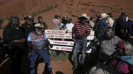 Traditional Owners pose for photos after placing the new sign of the permanent closure of the Uluru climb on the final day the climb is allowed.