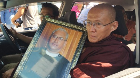 A Buddhist monk holds a portrait of Ko Ni on the way to his funeral.