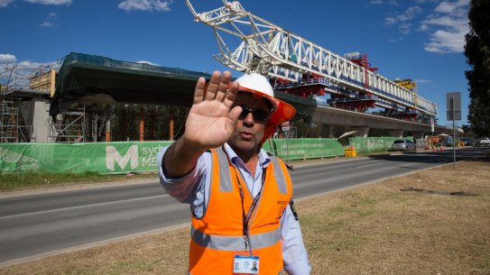A security guard attempts to stop photographs of the buckled span on the Skytrain viaduct in Sydney's north-west.