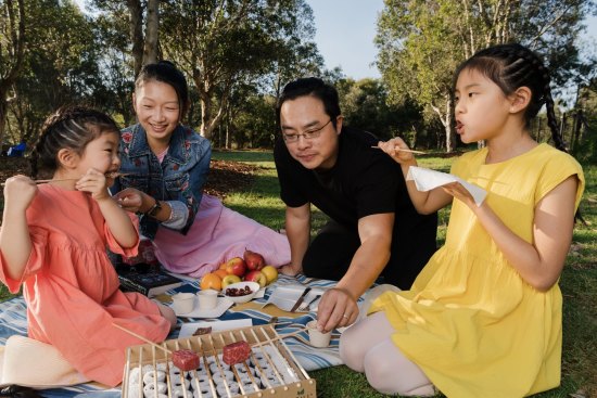 Firepop owners Alina Van and Raymond Hau charcoal grill with their daughters Arielle, 4, and Ariana, 9, at Sydney Park in Alexandria. 