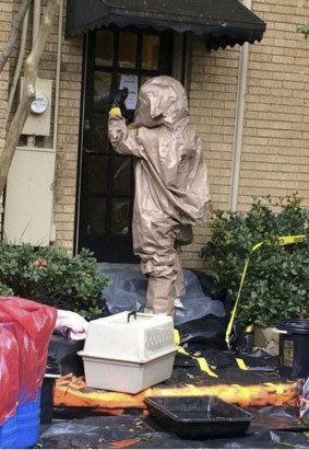 A man wearing a hazardous material suit prepares to remove a pet dog, named Bentley, from the home of a nurse infected with Ebola.