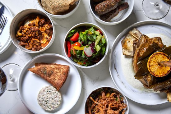 A selection of mezze including saj (bread), eggplant fatteh, fattoush, hummus, kingfish and kofta.