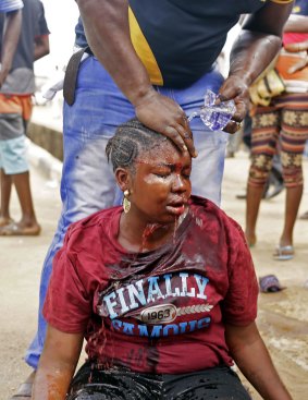 A man washes the face of a female voter beaten by a Nigerian policewoman at a poling station in Lagos during an altercation on Saturday. The policewoman was later arrested for misconduct.