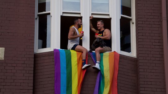 Two men celebrate above a rally on Oxford Street on the night the result was announced to Australia.