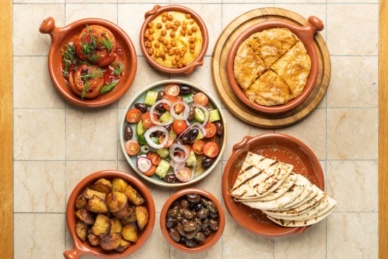 Clockwise from left: Gemista, fava dip, spanakopita, grilled pita, kalamalata olives, patates, village salad (centre). 