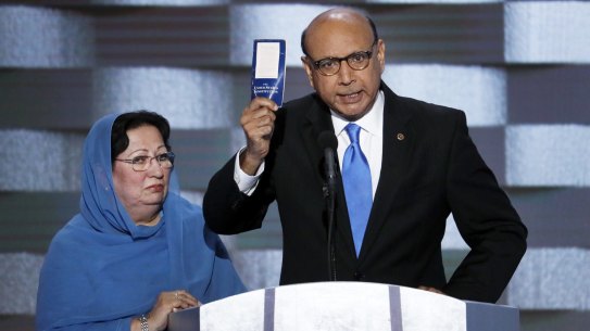 Khizr Khan, father of fallen US Army Captain Humayun Khan, holds up a copy of the US constitution at the Democratic National Convention as his wife Ghazala listens.