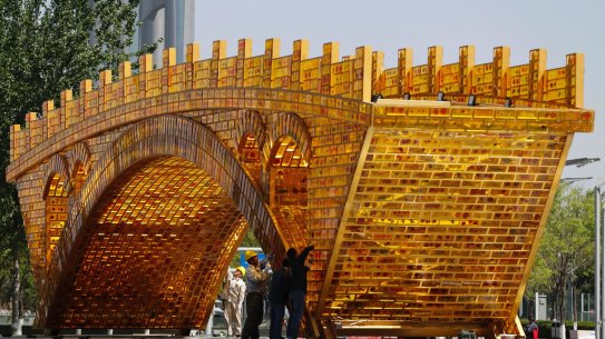 Workers install wires on a 'Golden Bridge of Silk Road' structure on a platform outside the National Convention Centre in Beijing.