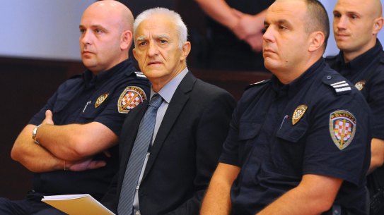 Dragan Vasiljkovic sits between two guards in a courtroom at the beginning of his trial in Split, Croatia.