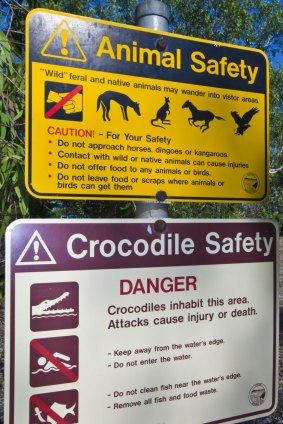 Graphic signs warn of Saltwater Crocodile and feral animal dangers.