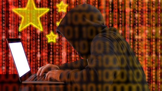 Hacker in a dark hoody sitting in front of a notebook with digital Chinese flag background and binary streams cybersecurity concept China spy generic