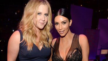 Once inside, Amy Schumer stays upright long enough to pose happily with Kim Kardashian.