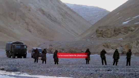 Chinese troops hold a banner reading "You've crossed the border, please go back" in Ladakh, India. 