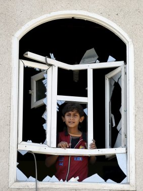 A boy looks through a window of his home damaged by an air strike near Sanaa Airport.