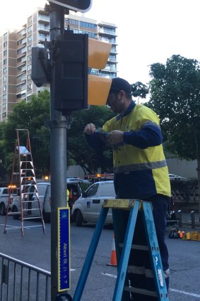 A worker installs yellow coverings to make Brisbane pedestrian lights look like those in New York for the Thor:Ragnarok filming.