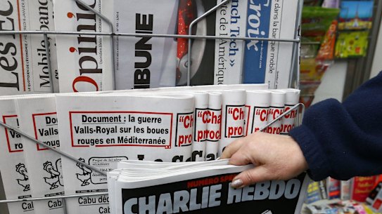A woman picks up the issue of Charlie Hebdo that marks one year after the attacks on the French satirical newspaper.