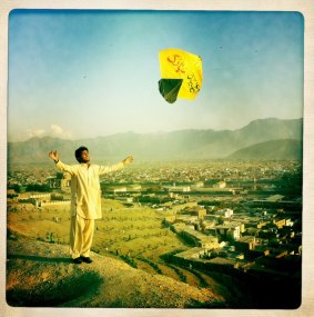 An Afghan man launches a kite from a ridge overlooking Kabul, Afghanistan.