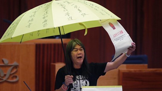 Elected pro-democracy lawmaker Leung Kwok-hung, known as "Long Hair," holds a yellow umbrella and a oversised mock copy of controversial, proposed anti-subversion legislation as he takes oath in the new legislature Council in Hong Kong.