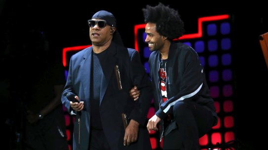 Stevie Wonder kneels on stage next to his son Kwame Morris before performing at the Global Citizen Festival in Central Park in New York.