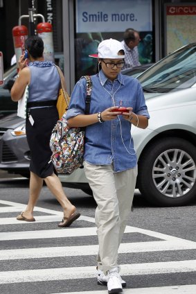 A pedestrian text messages while crossing the street in downtown Washington. A New Jersey legislator is targeting distracted walking. 