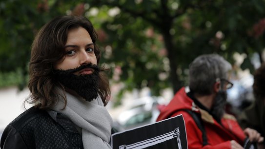 A woman with a fake beard attends a Paris protest on Wednesday to demand an end to widespread sexism in French politics.