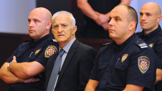 Dragan Vasiljkovic, center, sits between two guards in a courtroom at the beginning of his trial.