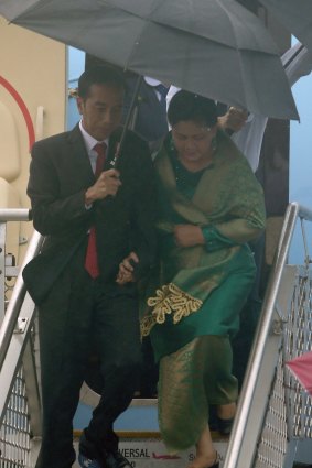 Joko Widodo and, left, his wife, Iriana, brave the elements at Sydney airport.