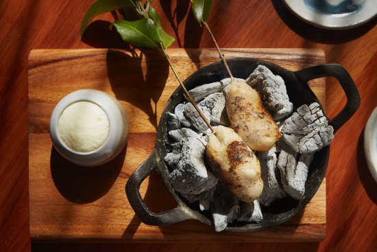 Potato damper on eucalyptus skewers, cooking on hot coals at your table.