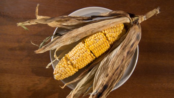 Buttered corn on the cob served in its husk.