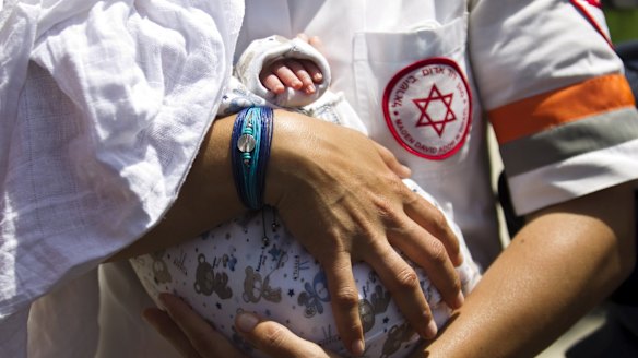 An Israeli medic holds a baby, born to a surrogate mother, who was evacuated from Nepal. 