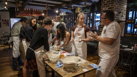 Pizza professional Luigi Esposito (right) guides students through the basics of dough kneading.
