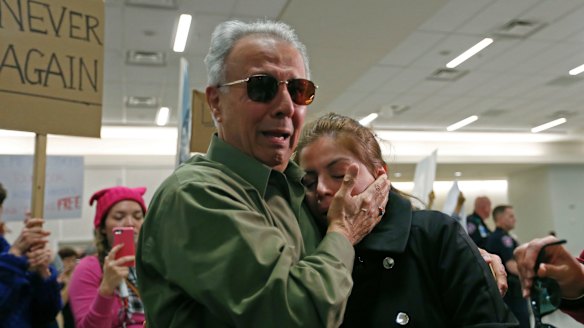 Iranian green card holder Shima Behgooy, right, cries on the shoulders of her father-in-law Ahmad Behgooy, a native of Iran who is now a US citizen, after she was released at Dallas-Fort Worth International Airport.
