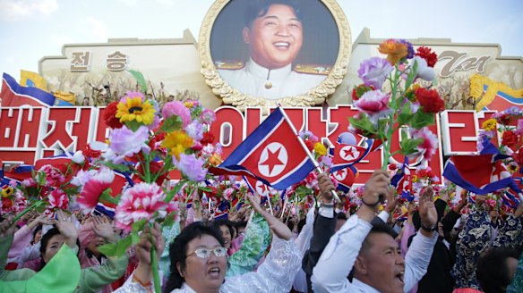 North Koreans cheer beneath an image of Kim Il-sung as they parade in Pyongyang.