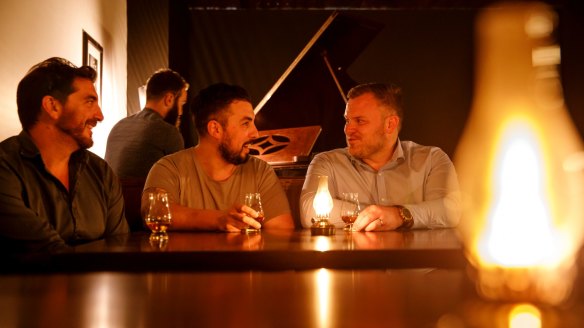 Molly bar owners Ant Arena, Lorenzo Focarile, and Dean Brown have a drink at the establishment's new digs in Odgers Lane while bartender Zac Guertin plays the piano. 
