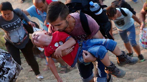 A young Syrian boy cries as his father carries him up a steep hill as they walk to a border crossing on the Greek and Macedonian border. 