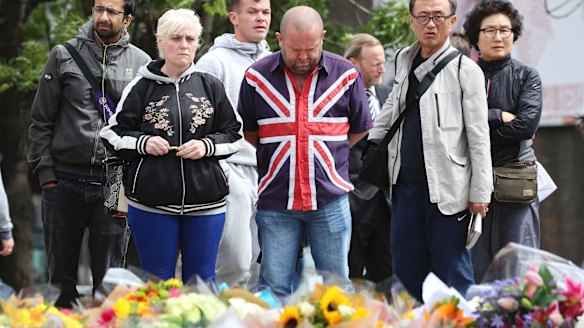 Londoners stop for a moment of reflection near London Bridge, where hundreds of bouquets have been placed.