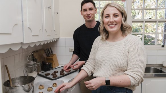 Raewyn Brack and her partner Adam Dowsett baking cookies in their Wollstonecraft apartment.