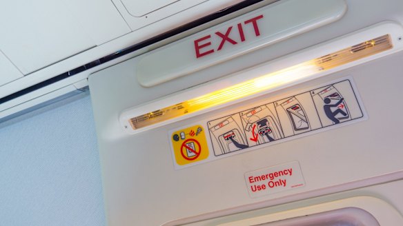 Why do some aircraft emergency exit doors have red tape over the window?