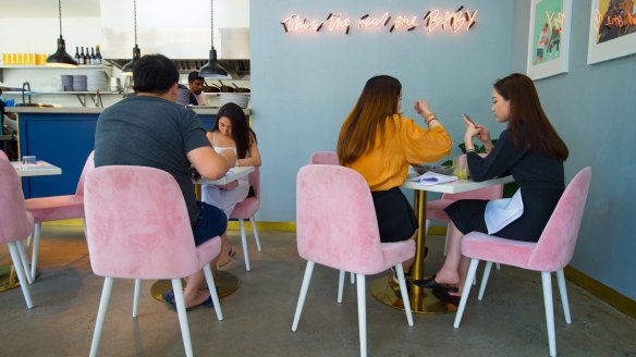 Baby's petite interior features pink neon and soft, baby-pink chairs.