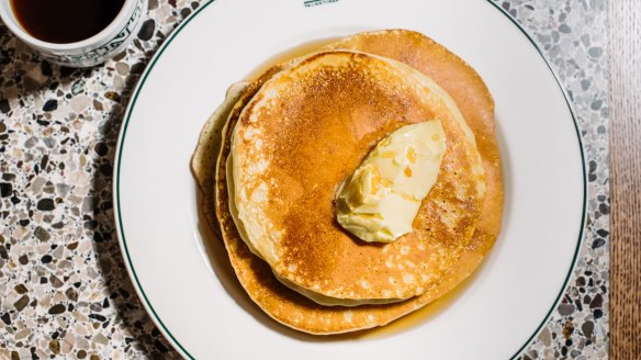 Short stack of pancakes with butter and maple syrup.