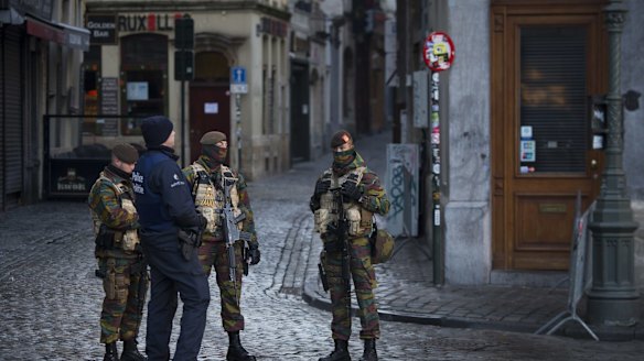 A police officer and armed soldiers stand guard at Grand Place square in Brussels, Belgium, on Monday as the search for a key suspect in the Paris terror attacks kept the Belgian capital in an unprecedented lockdown.