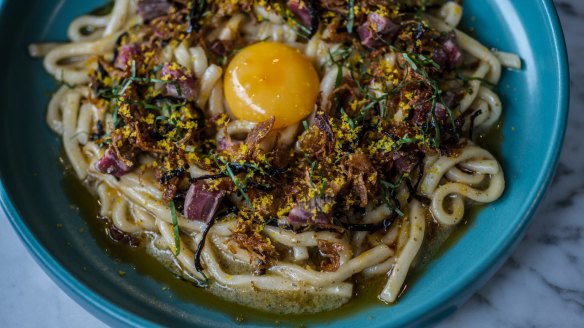 The udon noodles are topped with a raw egg like steak tartare.