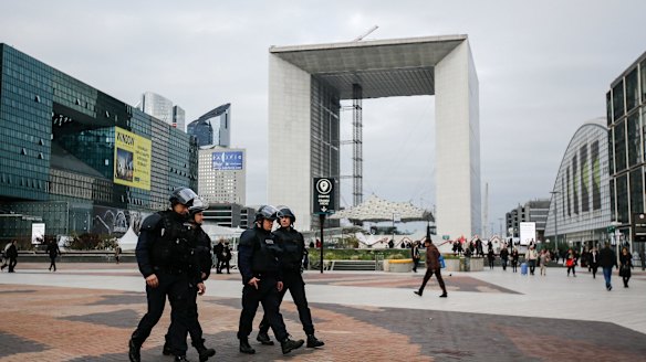 Armed police officers walk through La Defense business district in front of the Grande Arche in Paris on Monday.