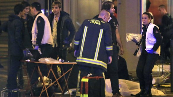 Rescue workers at the scene as victims lay on the pavement outside a Paris restaurant on Friday.
