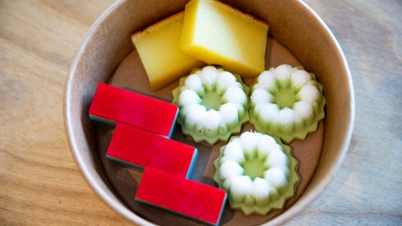 A kuih box featuring puteri ayu (green cake), kuih lapis (rainbow cake) and bingka ubi (yellow cake). 