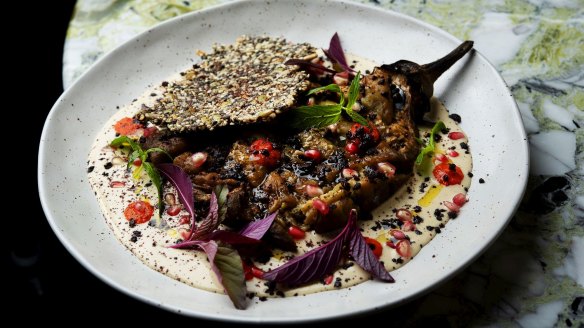 Fire-roasted eggplant, with tahini, fermented chilli, baby leaves and olives.