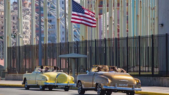 Tourists ride vintage American convertibles as they pass by the United States embassy in Havana, Cuba.