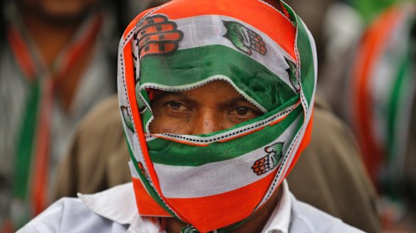 A supporter of India's main opposition Congress party covers himself with party's scarf during an election rally at Dhrangadhra in Gujarat.