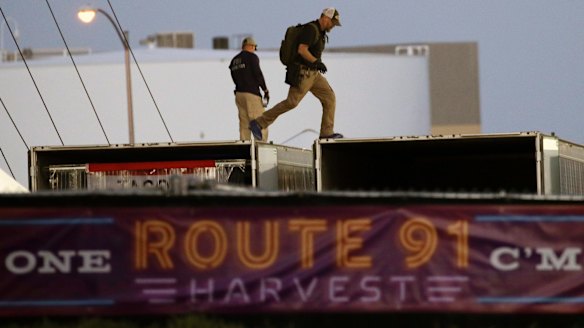 FBI agents walk along trailers as they continue to process the festival scene.